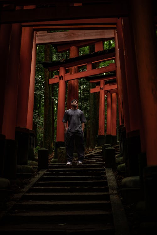 Man Standing on Stairs Under Torii Gates