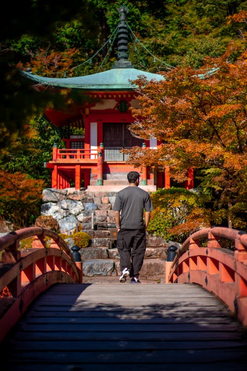 Man Walking on Bridge Towards a Japanese Temple
