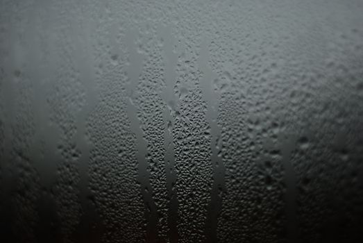 Detailed view of water droplets forming patterns on a window, showcasing moisture effects.
