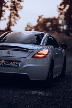 Back view of a sleek white sports car on a quiet road at twilight, evoking adventure.