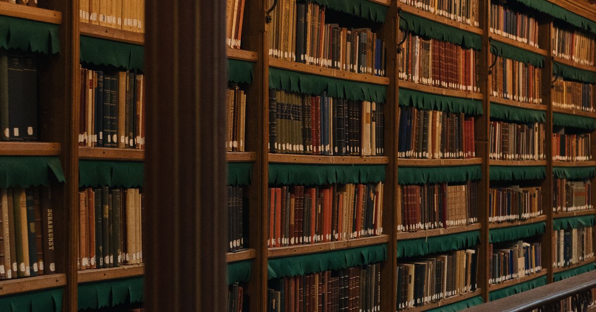 Rows of old books filling wooden library shelves