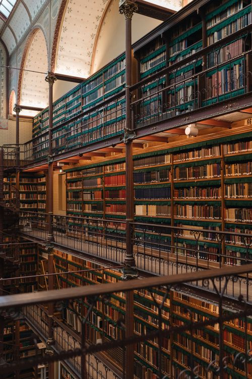 Free A classic library interior with high, densely packed bookshelves and elegant railings. Stock Photo