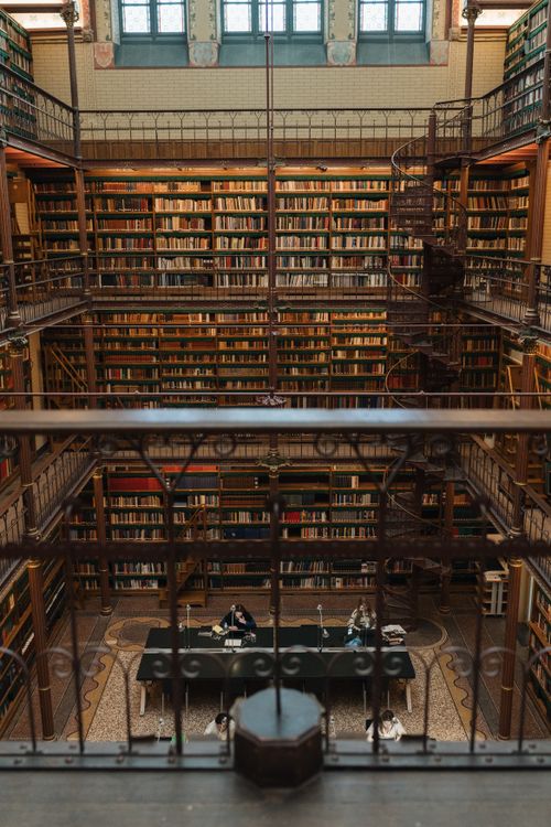 Free A captivating view of an ornate library interior featuring bookshelves and a spiral staircase. Stock Photo