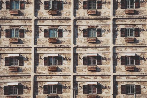Free Patterned sunlit facade of an urban building with open windows and wooden shutters. Stock Photo
