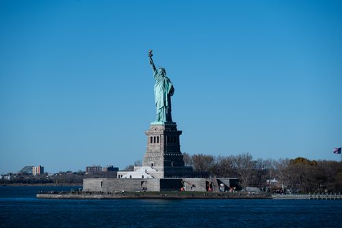 Free Iconic Statue of Liberty on Liberty Island with a clear blue sky in New York City. Stock Photo