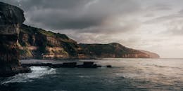 壮丽的沿海悬崖在壮观的日落天空下迎接着大海