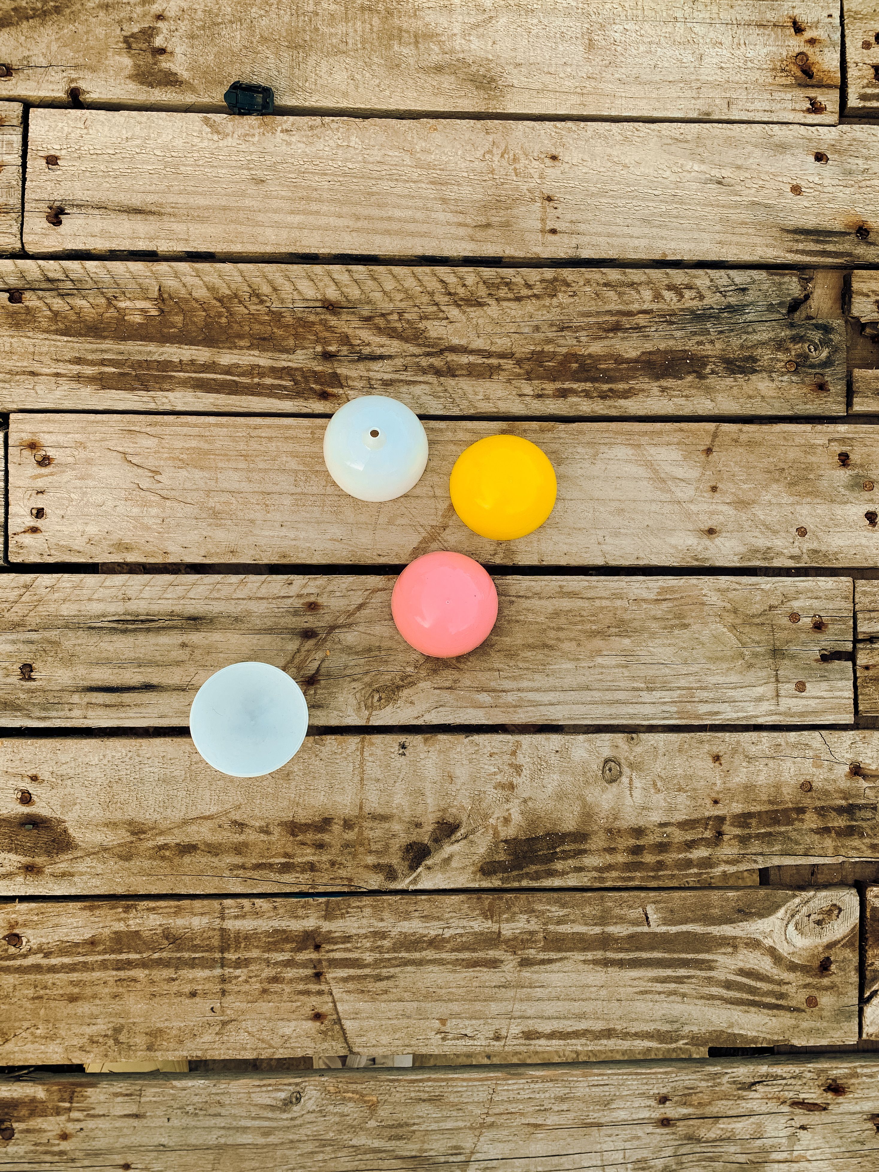 Multicolored balls arranged on a textured wooden platform for a vibrant, rustic look.