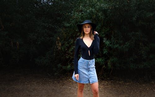 Young Woman in a Denim Skirt and a Hat Standing Outside