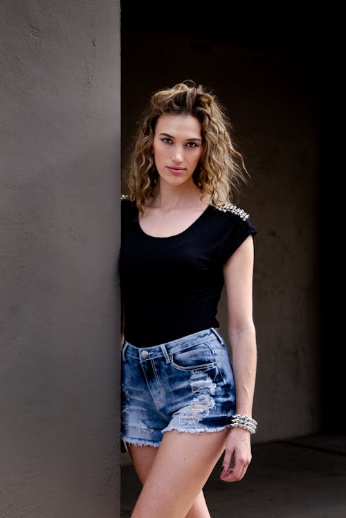 Young Woman in a Black Top and Denim Shorts Standing Outside 