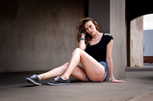 Woman Sitting by Wall and Posing