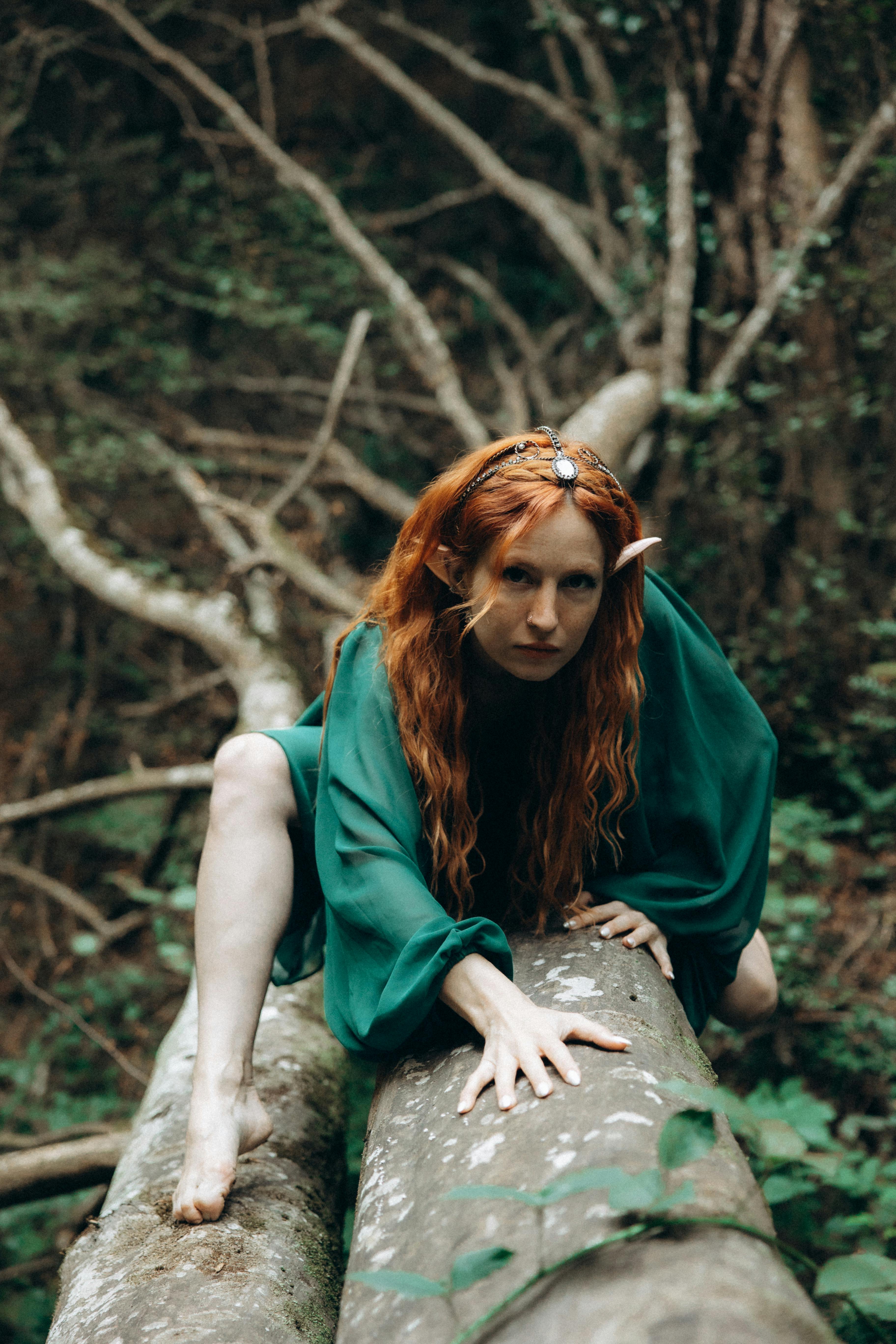 a woman with red hair sitting on a tree trunk