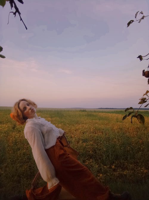 Young Woman Standing on a Meadow in the Evening 