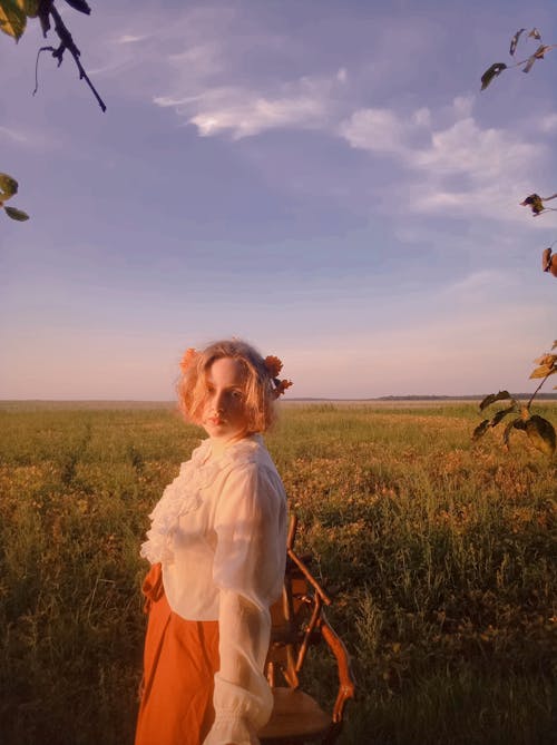 Young Woman Standing on a Meadow in the Evening 