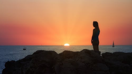 Woman Standing by the Sea at Sunset and Looking at the View 