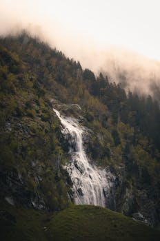 A beautiful waterfall flows down a mist-covered mountain in Ginzling, Tirol, Austria.