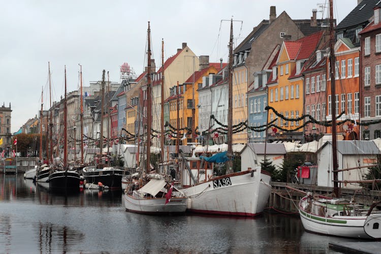 View Of Boats Moored In The Port And Colorful Houses In Nyhavn, Copenhagen, Denmark 