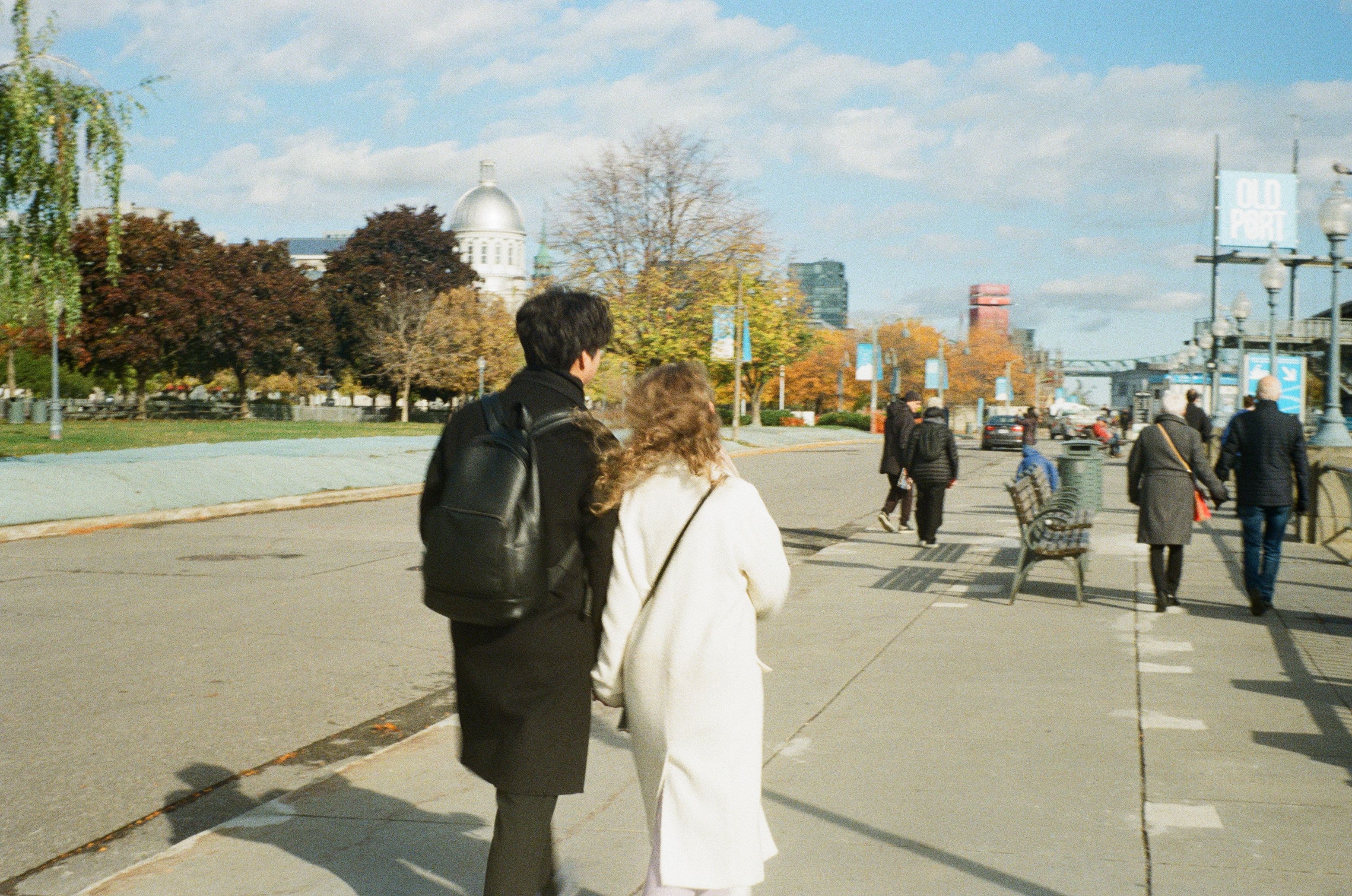 Couple strolling through a scenic autumn city street with historic buildings.
