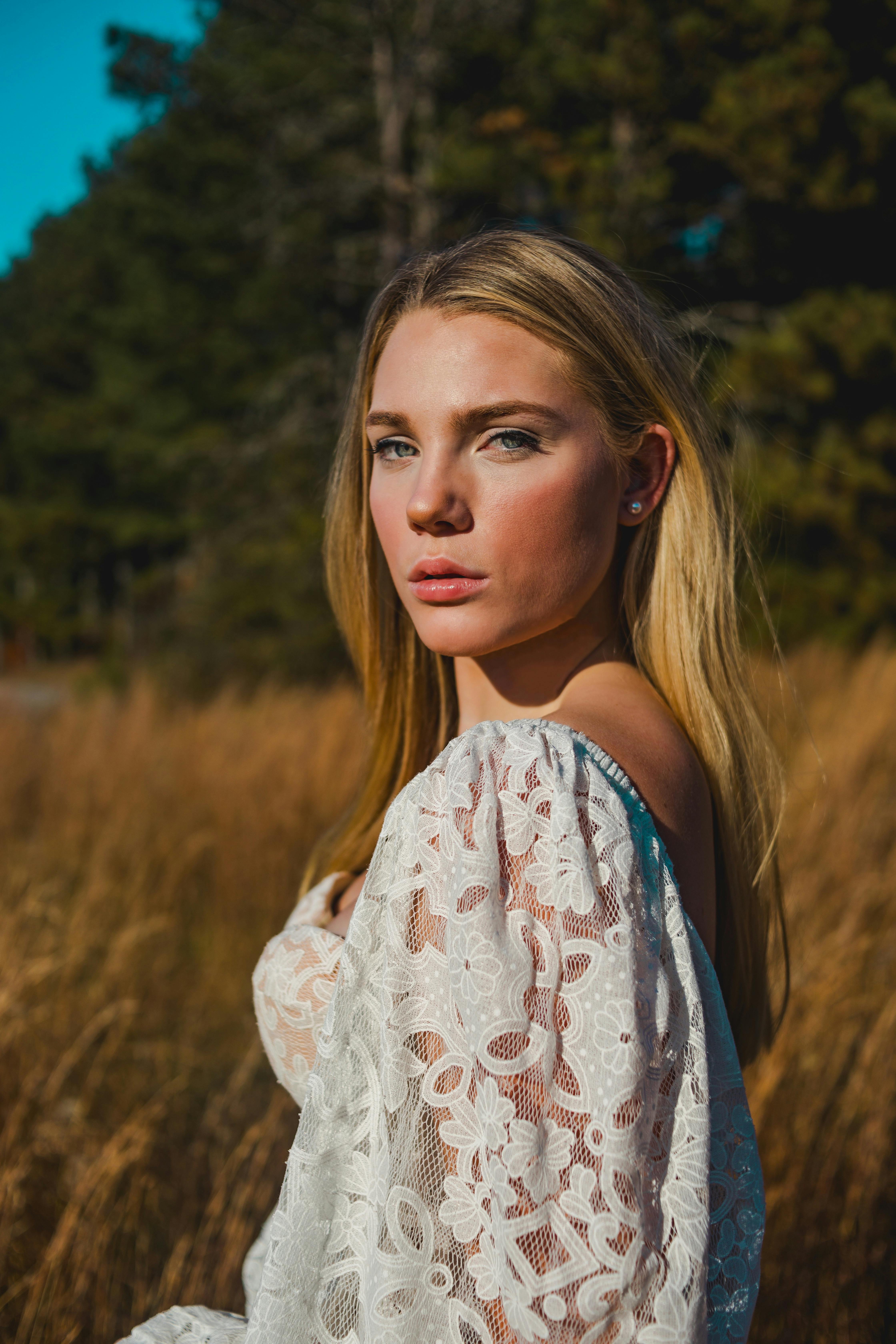 young woman in a white dress standing on a field