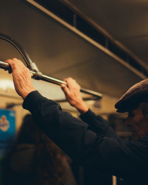 Free An adult man holds onto a handrail in a dimly lit subway train, embodying city life. Stock Photo