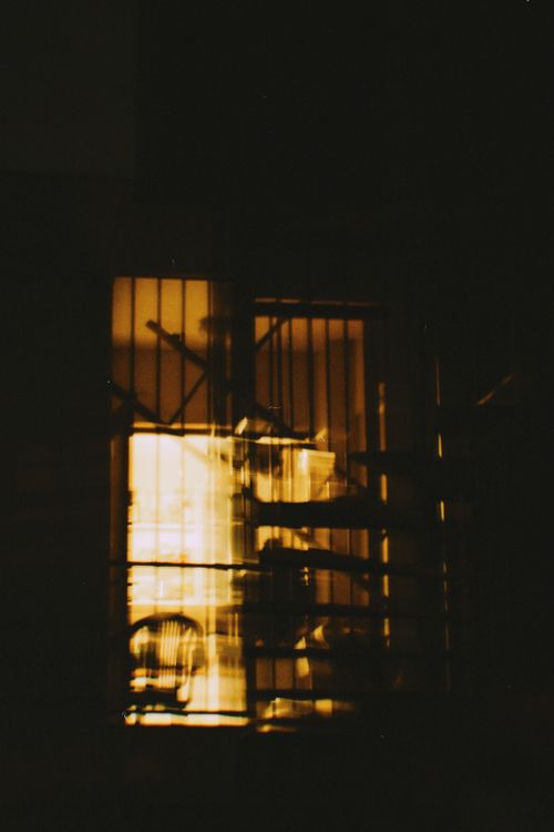 Free A mysterious view of an illuminated room with a spiral staircase seen through a window at night. Stock Photo