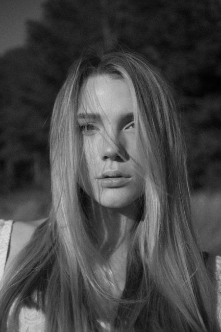 Elegant black and white portrait of a woman with long hair in natural light.
