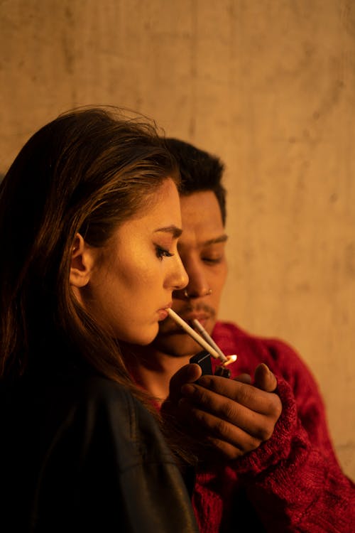 A Man and Woman Lighting Cigarettes