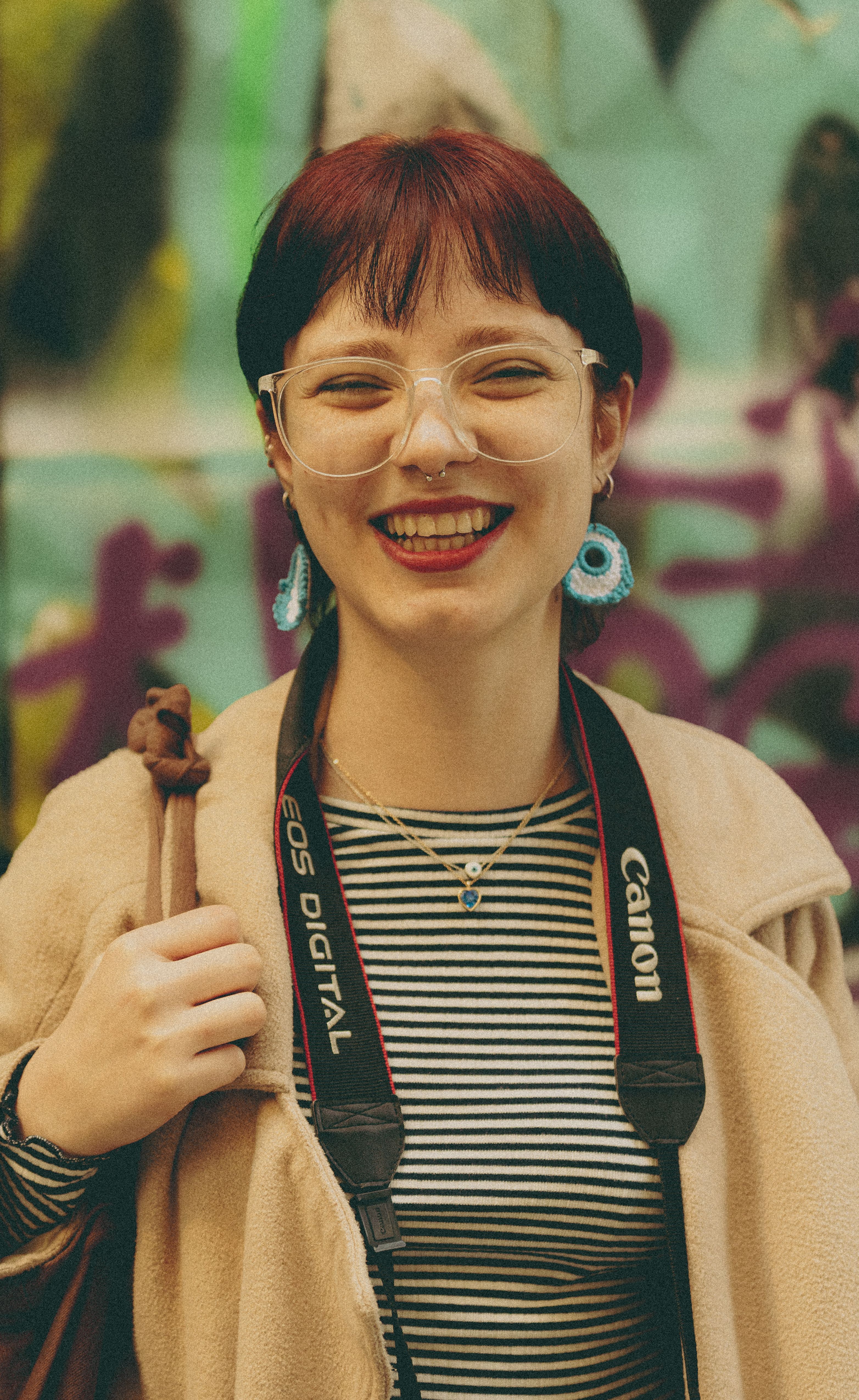 Young woman with eyeglasses and camera smiling warmly in İstanbul.