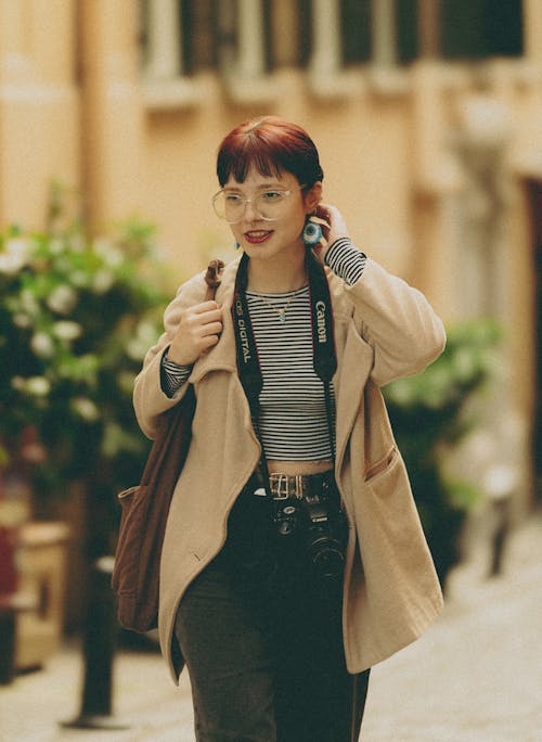 Young Woman with a Camera Walking Down the City Street 