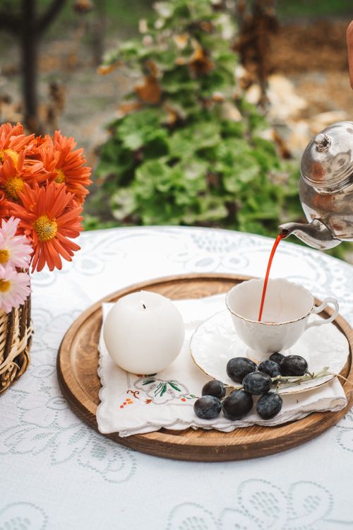 Free Charming outdoor tea setting with fresh fruit, vibrant flowers, and elegant tableware. Perfect for relaxation or a garden party. Stock Photo