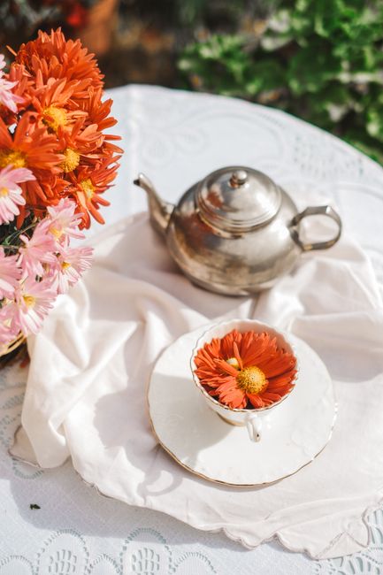 A charming outdoor tea setup with flowers and porcelain, ideal for lifestyle and garden themes.