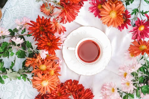 Tea in Cup Among Flowers on Table