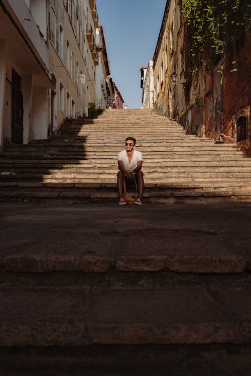 Man Sitting on Steps between Residential Buildings 