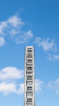 Vertical shot of a Ferris wheel under a bright blue sky, evoking a sense of adventure.