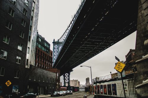 Free A moody cityscape scene with a large bridge overhead and surrounding modern architecture. Stock Photo