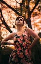 日落时分，一位身着花卉连衣裙的迷人女子在树林中自信地摆着姿势