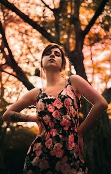 日落时分，一位身着花卉连衣裙的迷人女子在树林中自信地摆着姿势