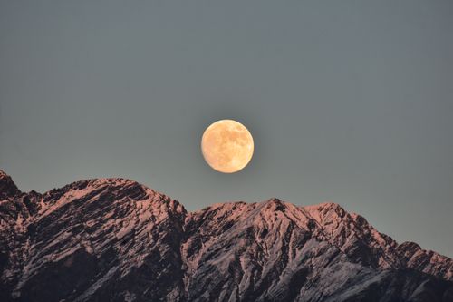 Free Majestic full moon over the snowcapped Kedarnath mountains at twilight, creating a serene landscape. Stock Photo