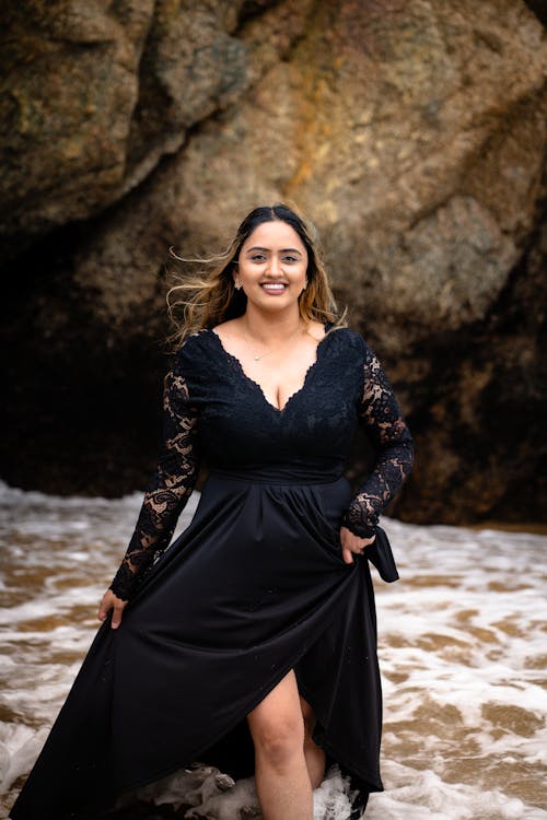 Smiling Model in Black Dress on Sea Shore