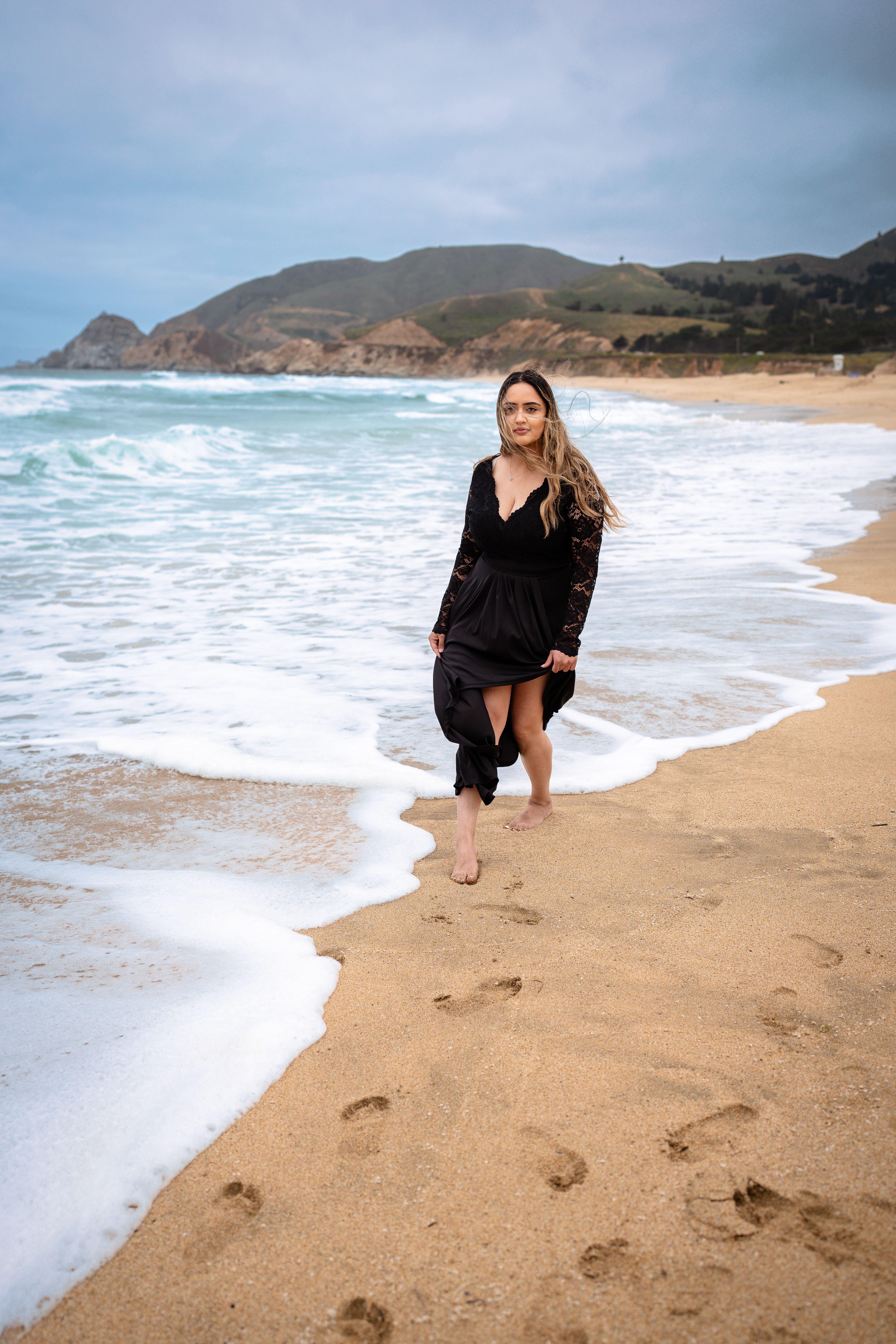 Model in Black Dress Walking on Beach  Free Stock Photo