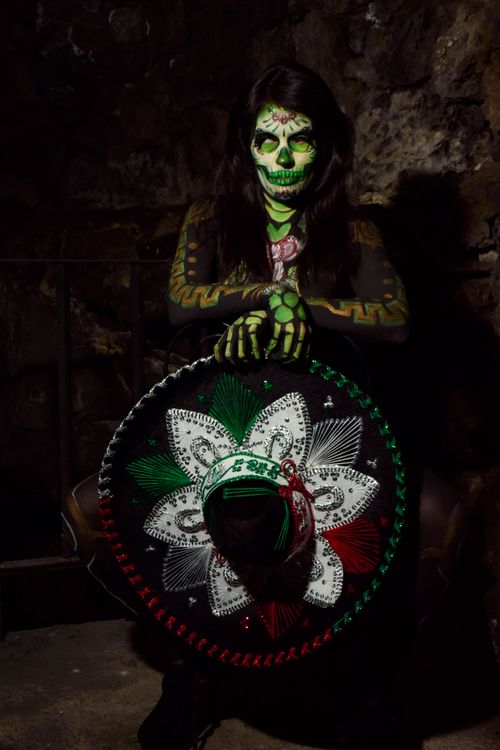 Free Dramatic portrait of woman with Dia de los Muertos makeup holding decorated sombrero. Stock Photo