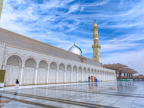 Beautiful view of the Prophet's Mosque in Medina with a prominent minaret and clear blue sky.