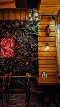 Warm café interior in Amasya with neon sign saying 'All You Need is Love' on a floral wall.