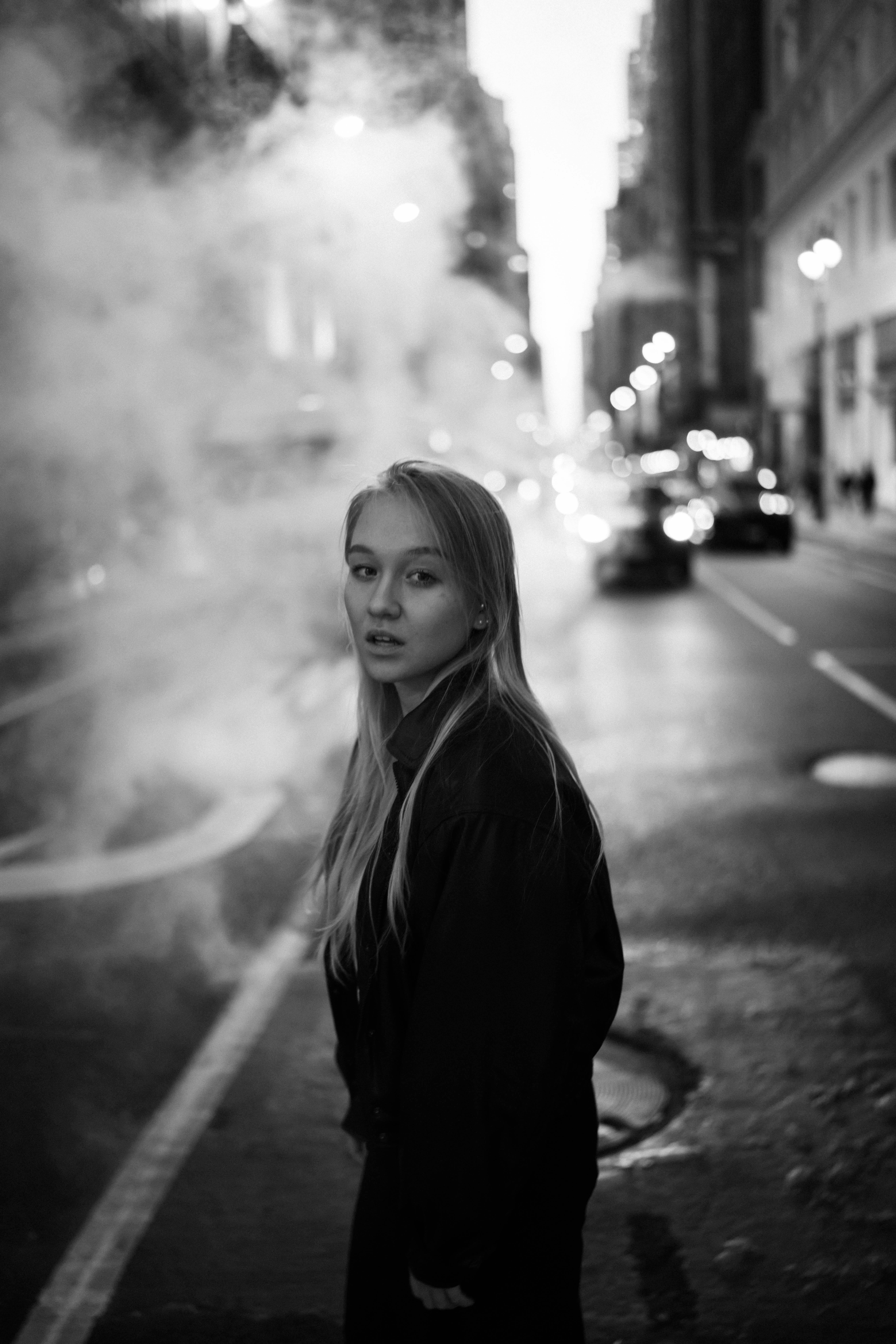 Black and white portrait of a woman on city streets with urban background.