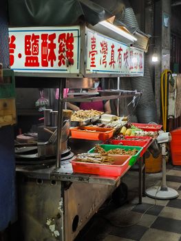 Explore a vibrant Asian street food market stall at night with traditional snacks and a bustling atmosphere.