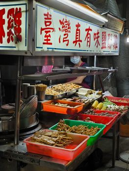 A vibrant Chinese street market stall displaying a variety of authentic street food items in colorful trays.