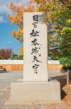 Stone monument surrounded by colorful autumn foliage in Matsumoto, Japan.