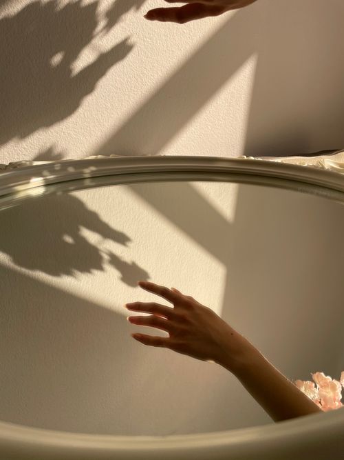 Free Artistic capture of a hand's reflection in a mirror with soft shadows, creating a calming ambiance. Stock Photo