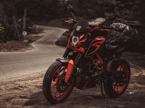 Free A sleek orange and black motorcycle parked on a winding road, perfect for a thrilling road trip. Stock Photo