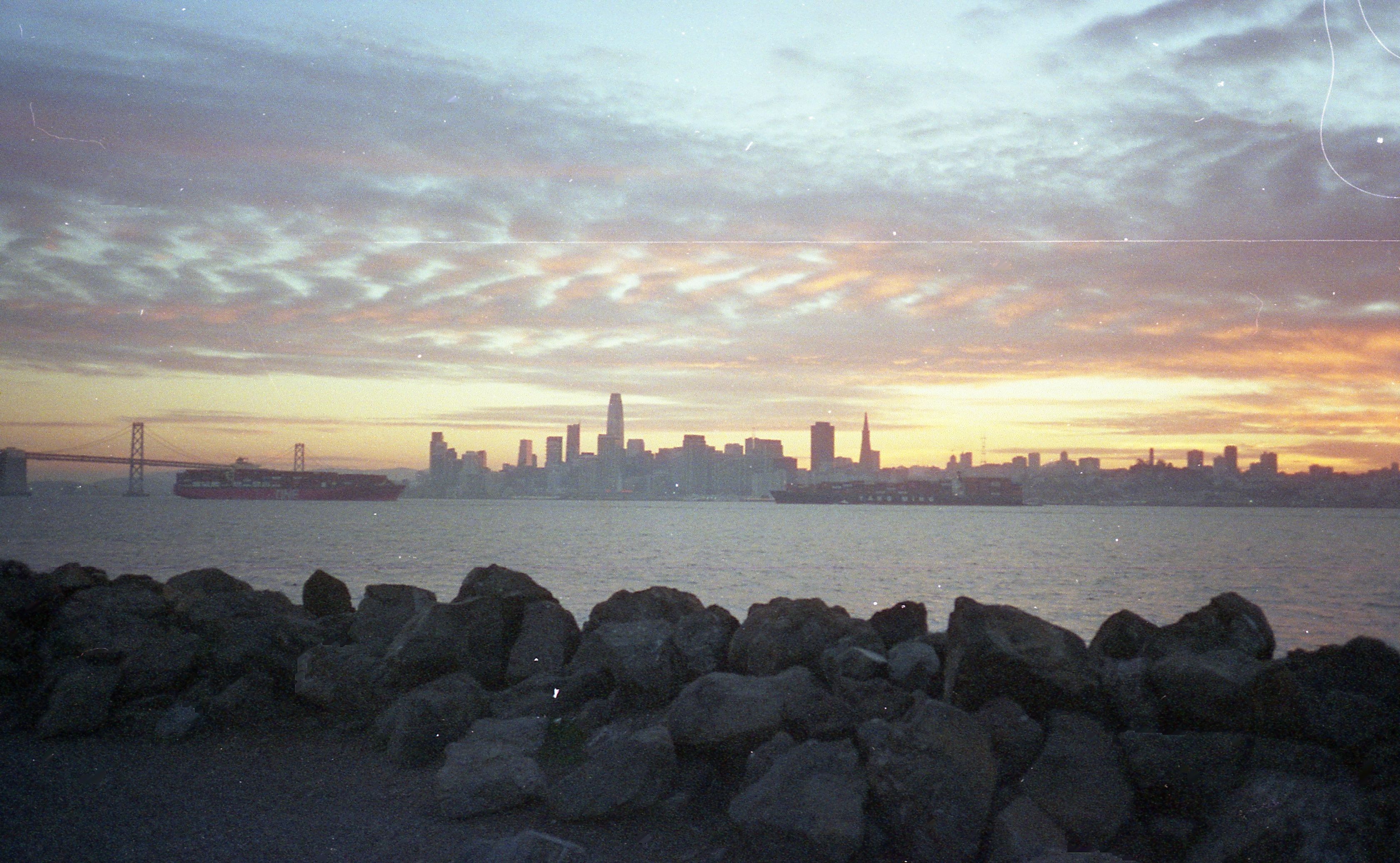 A stunning view of San Francisco's skyline and Bay Bridge at sunset, capturing serene coastal beauty.