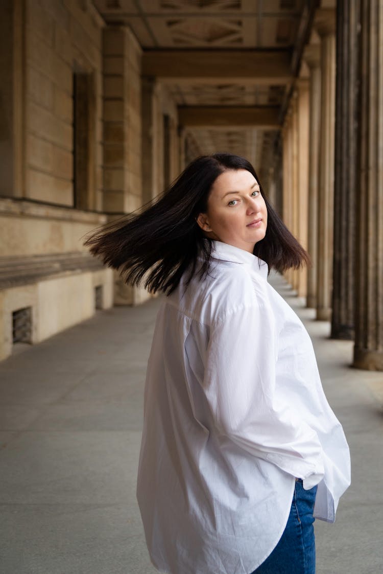 Young Woman In A White Shirt Walking And Looking Over The Shoulder 